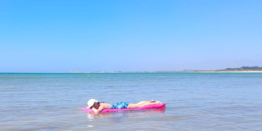 Susie Hopkins, ADHD Coach and registered nurse, lying on a lilo on the sea.